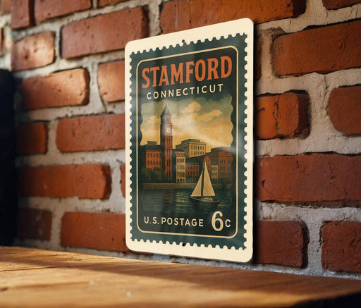 A vintage postage stamp from the United States of America, featuring a cityscape and a sailboat, mounted on a brick wall.