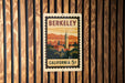 A vintage postage stamp from California, featuring a cityscape and a tower, is displayed on a wooden wall.