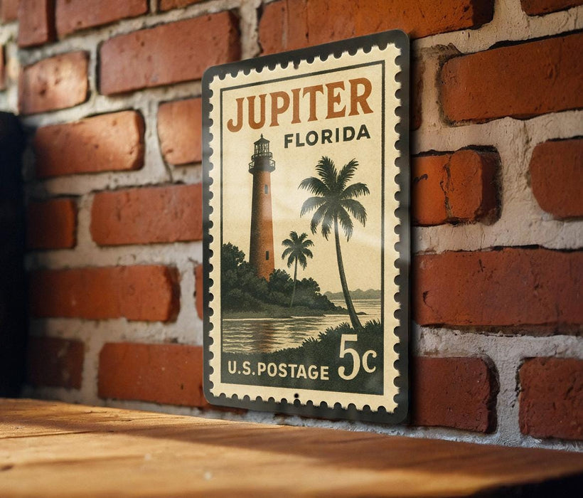 A vintage postage stamp featuring a lighthouse and palm trees, mounted on a brick wall.