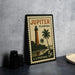 A vintage postage stamp from Jupiter, Florida, featuring a lighthouse and palm trees, is displayed on a table.