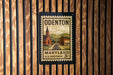 A vintage-style postage stamp from the United States Postal Service (U.S. Postage) for Odenton, Maryland, with a church and train tracks depicted on the stamp.