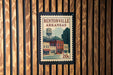 A vintage postage stamp from Bentonville, Arkansas, featuring a water tower and buildings, is displayed on a wooden wall.