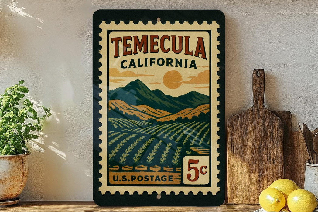 A vintage-style postage stamp from Temecula, California, featuring a landscape with mountains, fields, and a sun. The stamp is displayed on a shelf next to a wooden cutting board and some kitchen utensils.