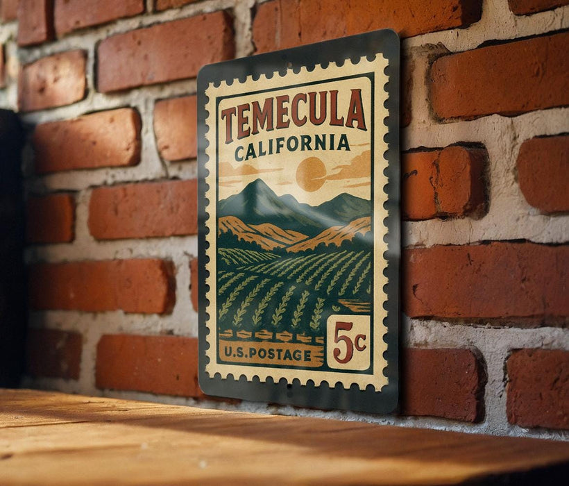 A vintage-style metal stamp depicting a scenic landscape of Temecula, California, with mountains, fields, and a sun in the sky.