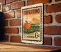 A vintage-style California 6c postage stamp featuring an illustration of an orange fruit, likely an apple, against a landscape background.