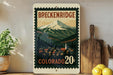 A framed vintage-style poster of Breckenridge, Colorado, featuring a mountain landscape with a small town in the foreground.