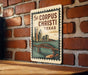 A vintage-style poster or sign featuring a cityscape with a bridge, mounted on a brick wall.
