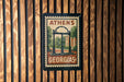 A vintage-style postage stamp from Georgia featuring a building and trees, mounted on a wooden wall.