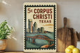 A vintage-style metal sign with a cityscape and bridge design, mounted on a wall next to a wooden cutting board and some potted plants.