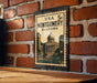 A framed image of the United States Capitol building in Montgomery, Alabama, mounted on a brick wall.