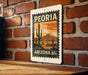 A vintage-style postage stamp from Arizona featuring a desert landscape with cacti and mountains, mounted on a brick wall.