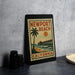 A framed poster of Newport Beach, California, featuring a palm tree and a pier, is displayed on a countertop.