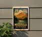 A framed vintage-style stamp depicting a scenic landscape of Missoula, Montana, with mountains, a river, and a town in the background.