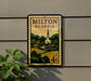 A postage stamp from the United States of America, featuring a rural landscape with a church and houses, mounted on a wall.