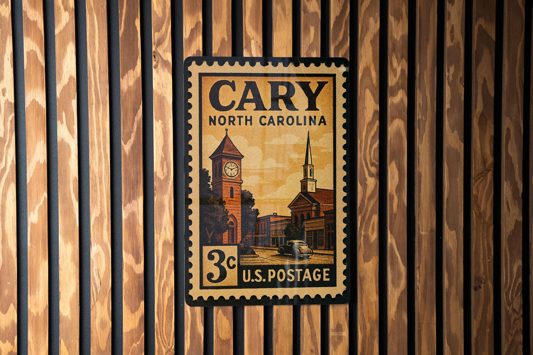A vintage-style postage stamp from North Carolina, featuring a clock tower and other architectural elements, is displayed on a wooden wall.