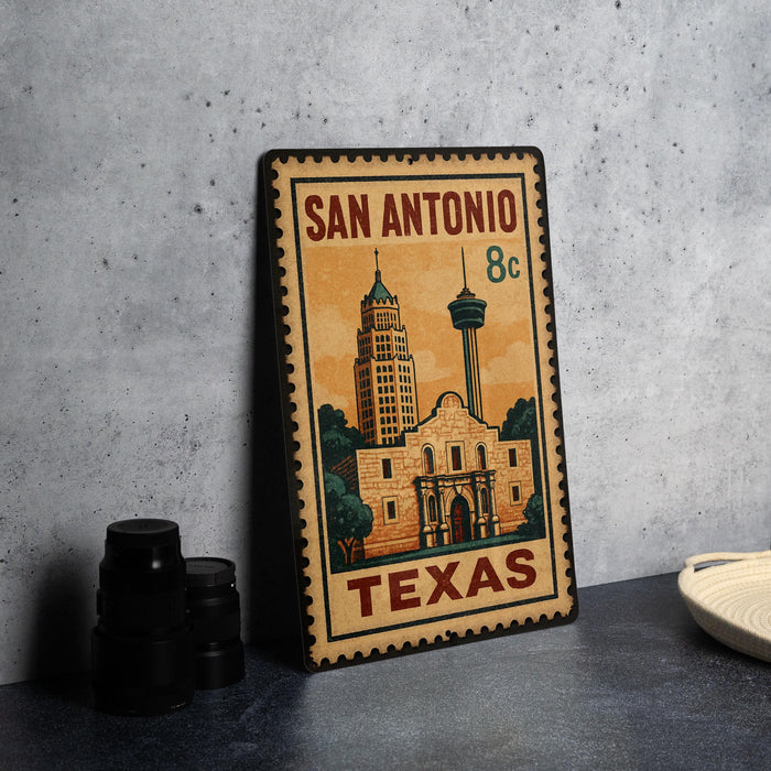 A vintage-style metal sign with the text "SAN ANTONIO 8c TEXAS" and an illustration of the Alamo, a famous landmark in San Antonio, Texas.