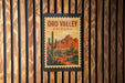 A vintage-style poster of the Oro Valley in Arizona, featuring a desert landscape with mountains and cacti, is displayed on a wooden wall.