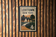 A vintage-style postage stamp depicting a street scene in Levitown, New York, with houses and trees.