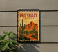 A framed poster of the Oro Valley in Arizona, featuring a desert landscape with cacti and mountains in the background.