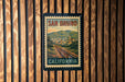A vintage-style postage stamp from San Bruno, California, featuring a scenic landscape with train tracks and a small town in the background.