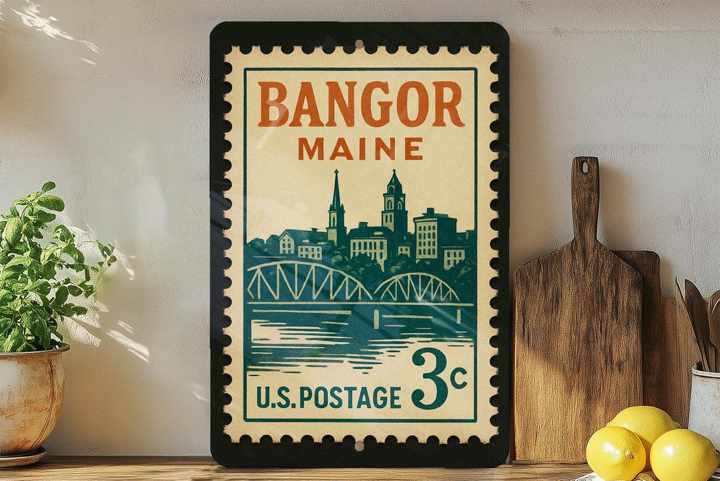 A framed vintage postage stamp from Bangor, Maine, featuring a cityscape and a bridge, is displayed on a shelf next to a wooden cutting board and some lemons.