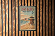 A vintage-style poster of Long Beach, New York, featuring a lifeguard tower and the ocean, is displayed on a wooden wall.