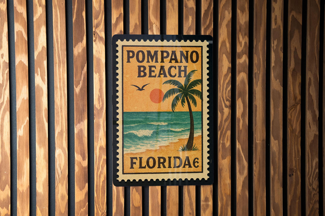 A vintage-style stamp or sign for Pompano Beach, Florida, featuring a palm tree and a sunset over the ocean.