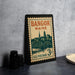 A vintage postage stamp from Maine, featuring a cityscape and a bridge, is displayed on a table.
