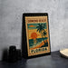 A framed poster of Ormond Beach, Florida, featuring a palm tree and sunset, is displayed on a countertop.
