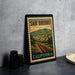 A framed vintage postage stamp depicting a scenic view of San Bruno, California, with a train track and mountains in the background.