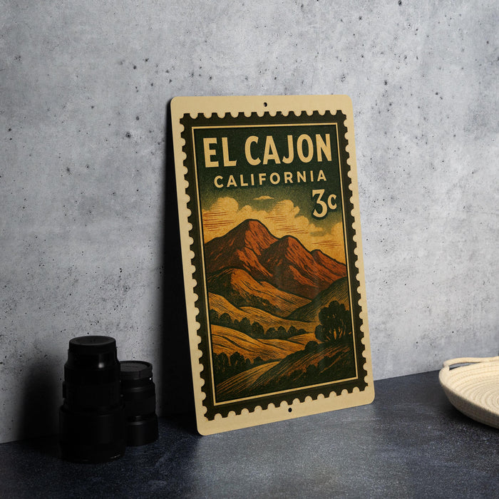 A vintage-style metal sign with a landscape illustration and text, placed on a gray surface next to some black camera lenses.