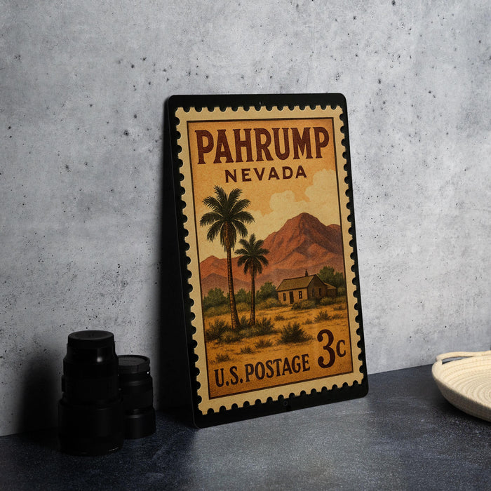 A vintage U.S. postage stamp from Nevada, featuring a desert landscape with palm trees and a house, is displayed on a table.