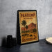 A vintage U.S. postage stamp from Nevada, featuring a desert landscape with palm trees and a house, is displayed on a table.
