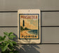 A sign for Pensacola, Florida, featuring a lighthouse and beach scene.