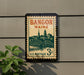 A vintage postage stamp from Maine, featuring a cityscape and a bridge, is displayed on a wall.