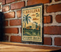 A vintage-style postage stamp from Carolina, featuring a palm tree and buildings, is displayed on a brick wall.