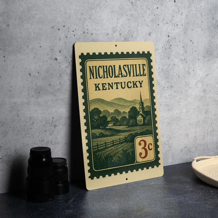 A vintage-style metal sign with the text "NICHOLASVILLE KENTUCKY" and a depiction of a rural landscape, along with a denomination of 3 cents, is displayed on a table.