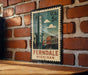 A vintage-style postage stamp featuring the name 'Ferndale' and the location 'Michigan' is displayed on a brick wall.