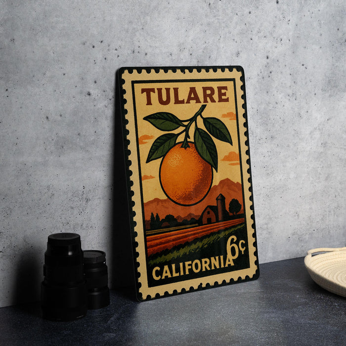 A vintage-style metal stamp depicting an orange and a rural landscape, with the text "TULARE" and "CALIFORNIA" printed on it.