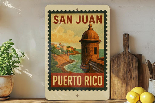 A vintage-style poster of San Juan, Puerto Rico, featuring a castle and a coastal landscape, is displayed on a wall next to a wooden cutting board and a potted plant.