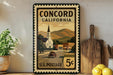 A vintage-style postage stamp from Concord, California, featuring a church and a road, displayed on a shelf next to a wooden cutting board and some lemons.