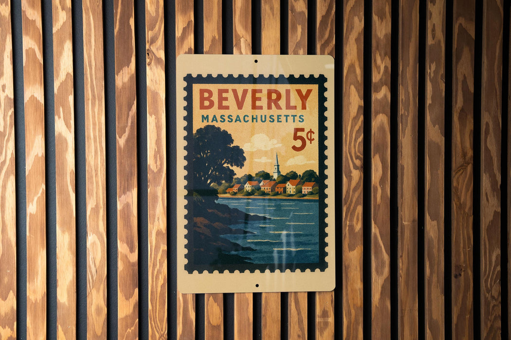 A vintage postage stamp from Beverly, Massachusetts, featuring a scenic landscape with a river and houses, is displayed on a wooden wall.