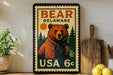 A vintage-style metal stamp featuring a bear on a green background, with the text "BEAR DELAWARE USA 6c" printed on it.