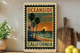 a vintage-style California postage stamp with a palm tree and sunset scene, displayed on a shelf next to a wooden cutting board and some lemons.