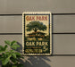 A vintage-style postage stamp featuring an illustration of a house and a tree, mounted on a wall next to a plant.