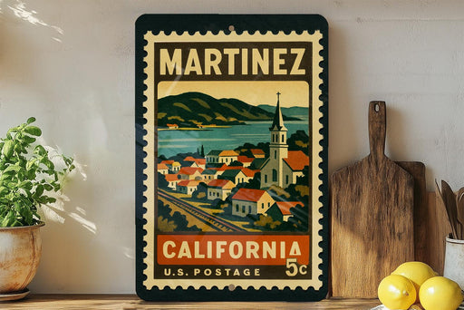 A vintage-style postage stamp from California, featuring a colorful illustration of a town and mountains, displayed on a shelf next to a wooden cutting board and some potted plants.