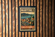 A vintage postage stamp from California, featuring a town and mountains, is displayed on a wooden wall.