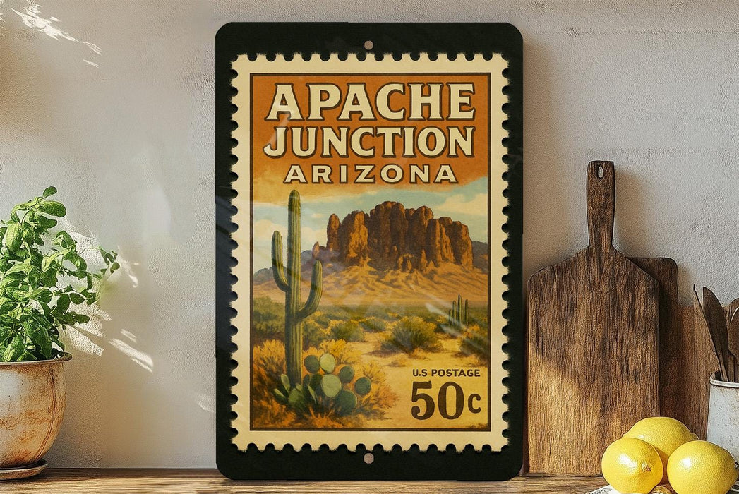A framed vintage postage stamp depicting the Apache Junction in Arizona, with a desert landscape and cacti, is displayed on a shelf next to a wooden cutting board and a potted plant.