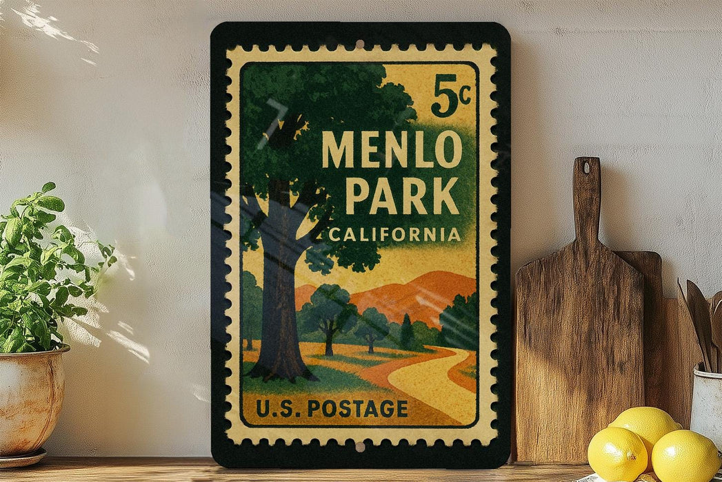 A vintage-style postage stamp from Menlo Park, California, featuring a scenic landscape with a winding road and trees. The stamp is displayed on a shelf next to a wooden cutting board and a potted plant.