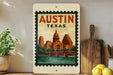 A framed poster of the Austin, Texas skyline with a bridge and water, displayed on a wall next to kitchen utensils and a potted plant.